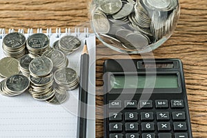 Selective focus on stack of coins with pencil and note book, calculator as financial saving concept